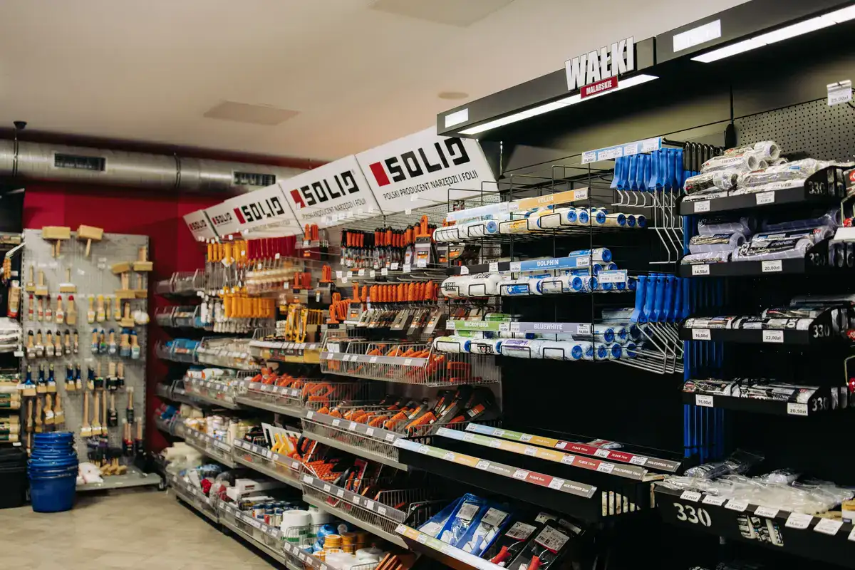 Alejka w dużej hurtowni budowlanej EKOBau z regałami pełnymi narzędzi, wałków i pędzli marek Solid oraz Wałki Malarskie.