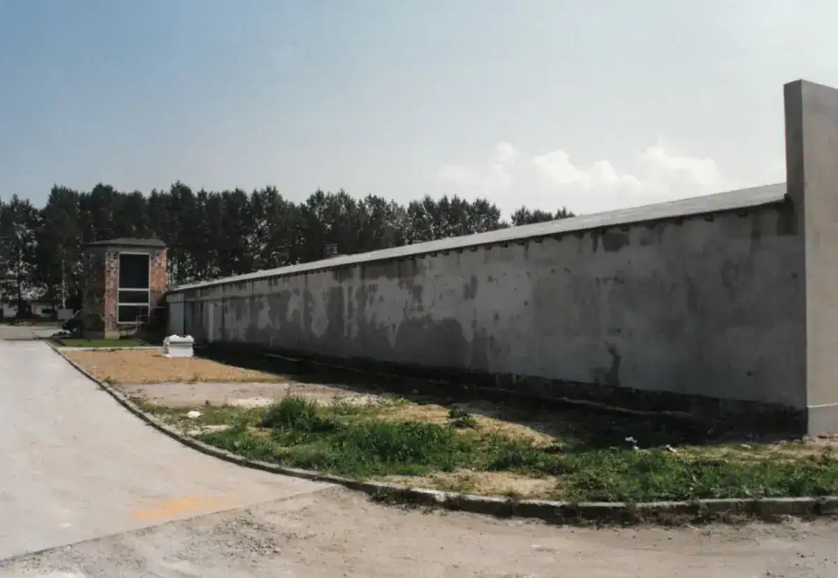 Ściana magazynu hurtowni w trakcie budowy – surowy, szary mur i utwardzona droga dojazdowa.